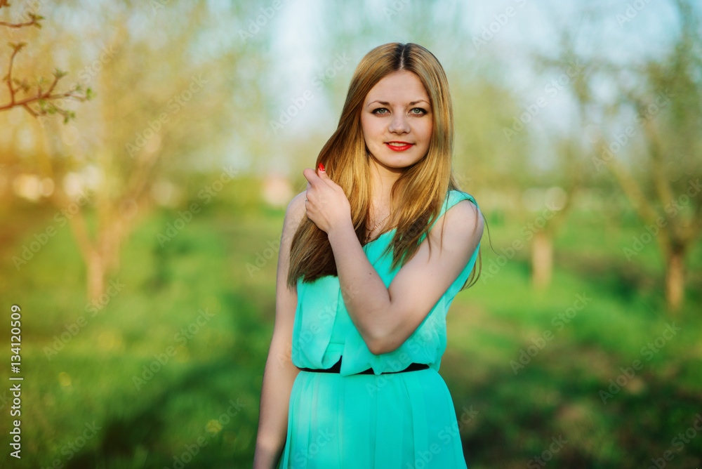 Woman in a beautiful long turqoise dress posing on a meadow in t Woman in a beautiful long turqoise dress posing on a meadow in t