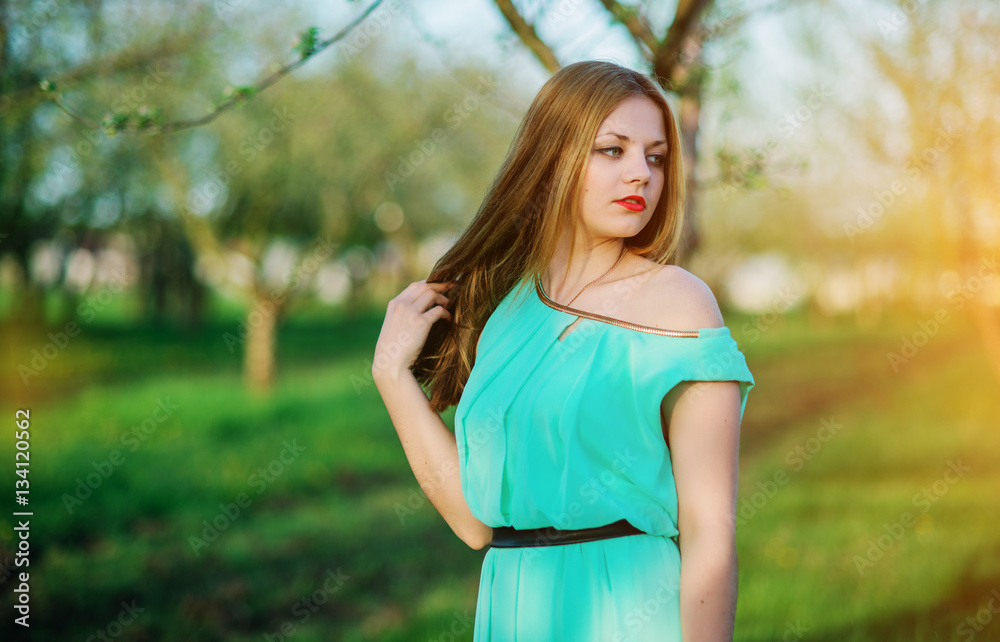 Woman in a beautiful long turqoise dress posing on a meadow in t Woman in a beautiful long turqoise dress posing on a meadow in t