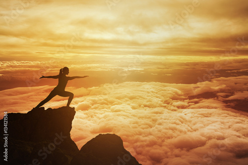 Woman meditating in yoga position on the top of mountain photo