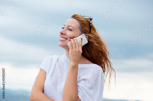 young happy woman talking on mobile phone on a beach with ocean sea background, Sardinia Italy