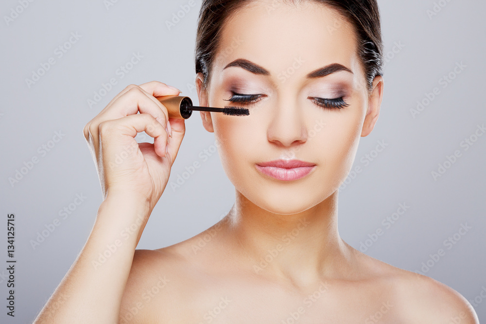 Girl with closed eyes painting eyelashes with mascara Girl with closed eyes painting eyelashes with mascara