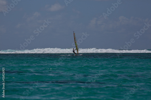 A windsurfer approaching a line of breakers in Mauritius.