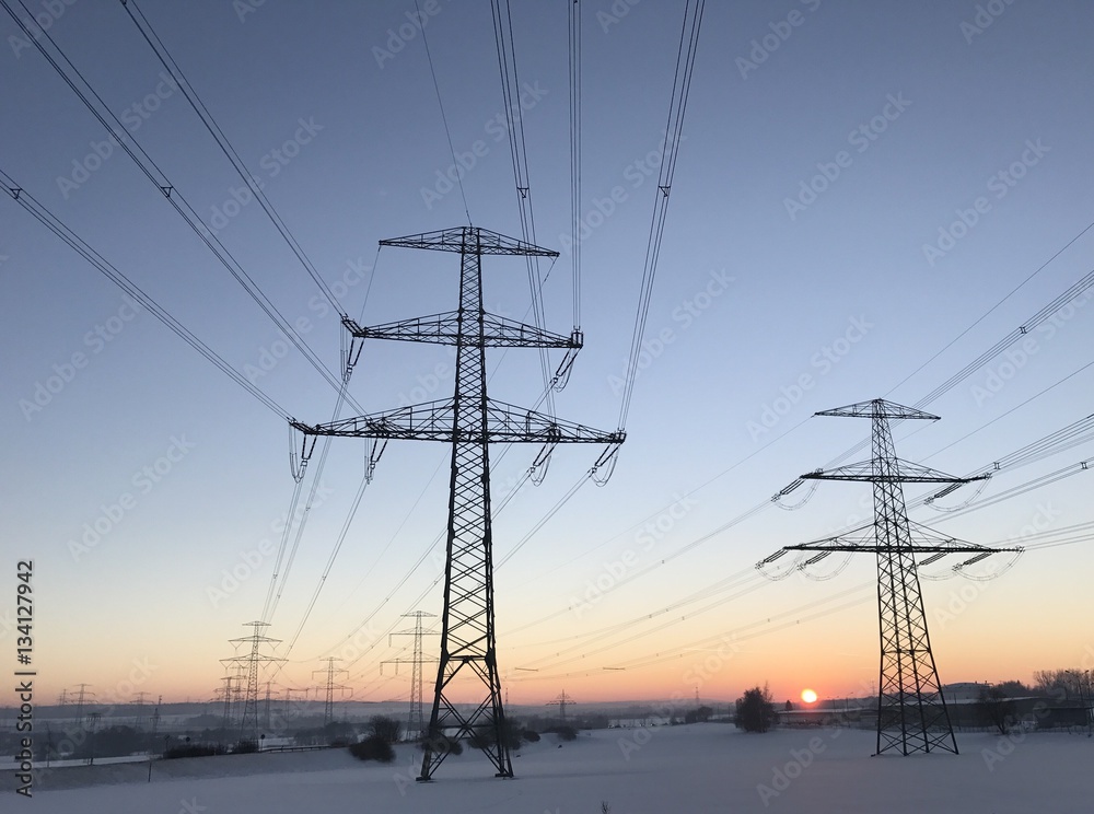 Strommasten im Winter bei Sonnenuntergang