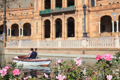 Roses and blurred touristic boat with loving couple, Spain square, Seville, Spain 