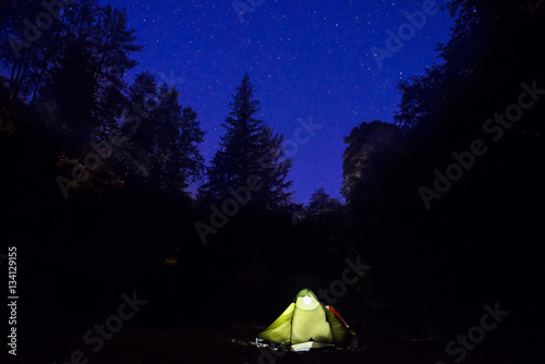 Illuminated tent at night in the forest