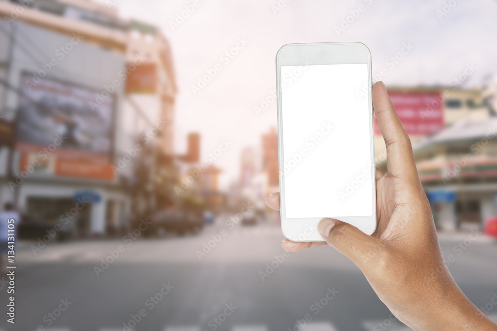 hand holding smartphone on traffic road and urban scene.