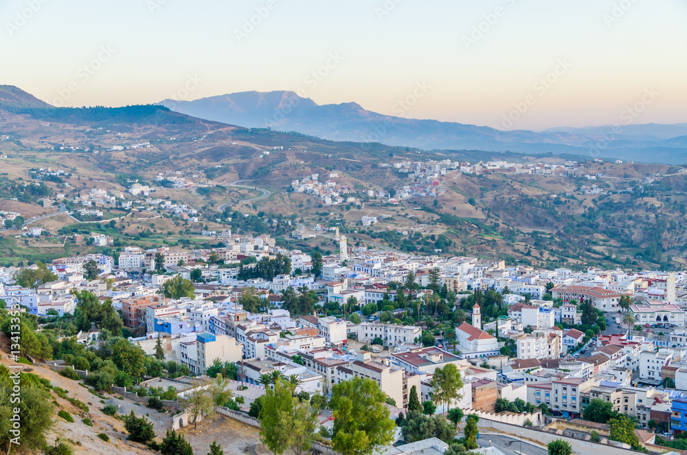 Beautiful historical town Chefchaouen with its blue washed buildings viewed from a hill during sunset, Morocco