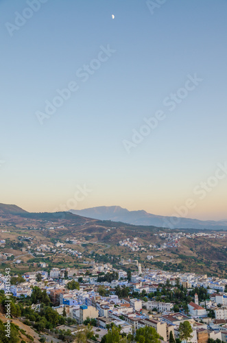Beautiful historical town Chefchaouen with its blue washed buildings viewed from a hill during sunset, Morocco