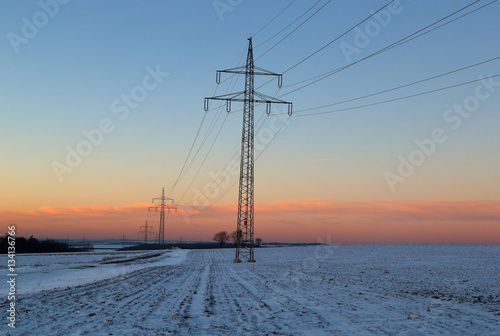 Winter landscape with fields and meadows / Sunset in the winter / High-voltage masts.