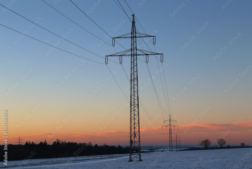 Winter landscape with fields and meadows / Sunset in the winter / High-voltage masts.
