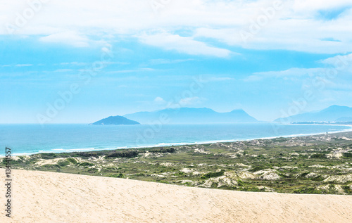 Seascape: Beach, sand, green vegetation, blue ocean and some mountains on the background. Wonderful view from Dunas da Joaquina near Joaquina beach. photo