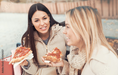 Friends eating pizza. Two young women eating pizza after shoppin