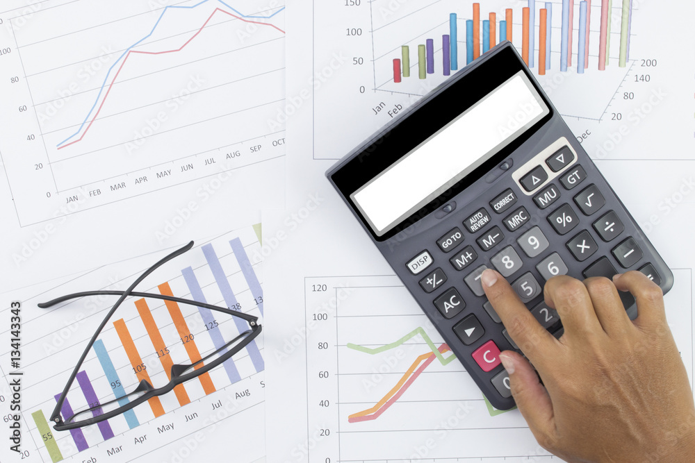 business concept : glasses and calculator with hand on stock market report as background business concept : glasses and calculator with hand on stock market report as background