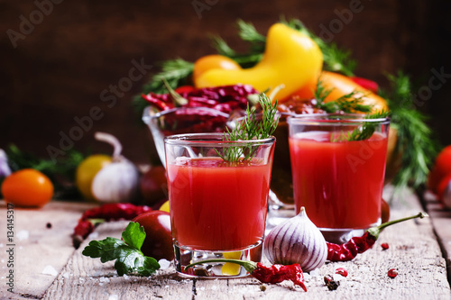 Spicy tomato juice with vegetables on a vintage wooden backgroun