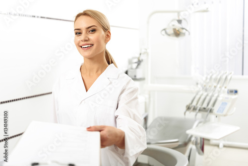 Stomatologist giving blank to her client in office photo