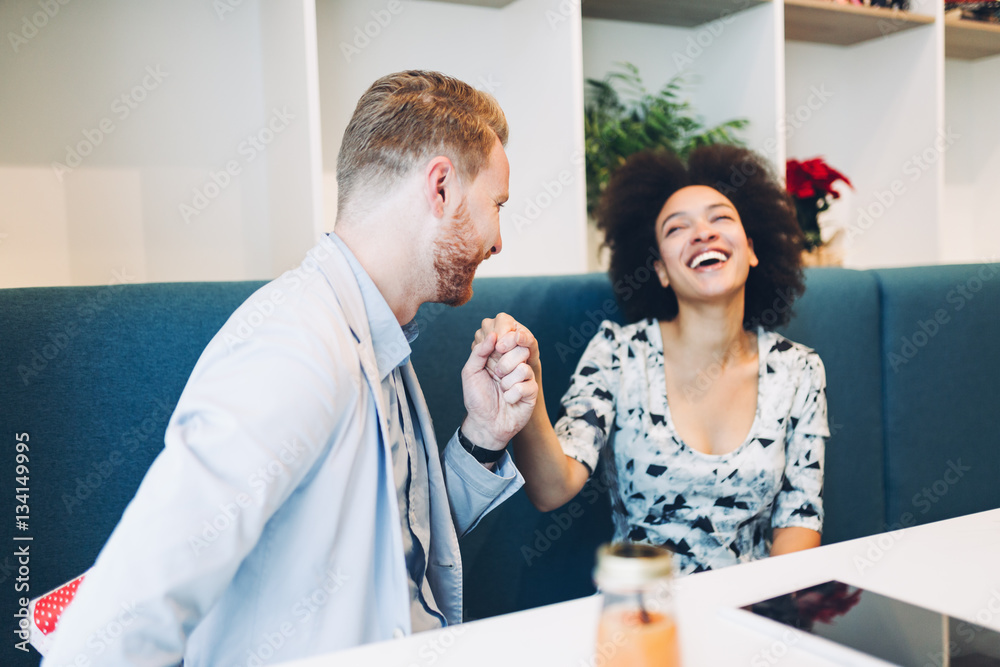 Obraz premium Happy middle aged multiracial couple dating. Handsome redhead man with beautiful Afro american woman having some good time in cafe bar or restaurant. Woman receiving gift from man.
