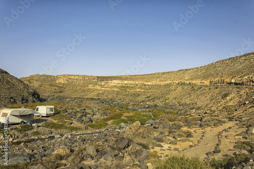 Daylight landscape with a motorhome parked somewhere between hills on Fuerteventura, Canary Islands, Spain appearing to almost allure tourist to practice this form of tourism.