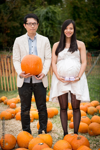 Couple maternity photo with pumpkin in pumpkin patch