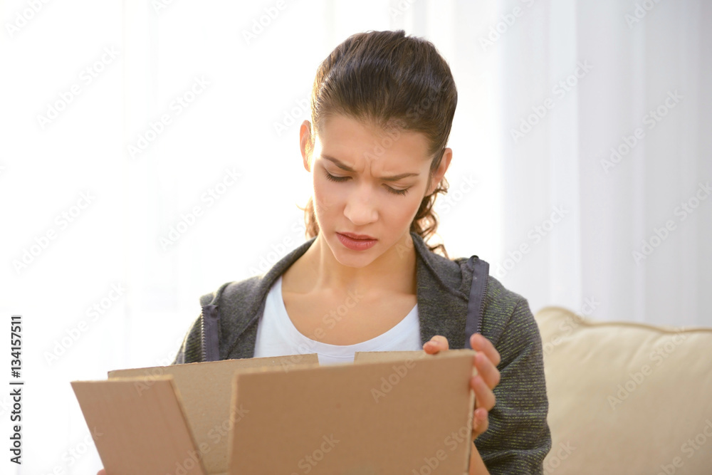Beautiful young woman opening box with parcel at home Beautiful young woman opening box with parcel at home