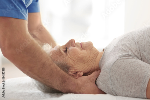 Physiotherapist working with elderly patient in clinic, closeup