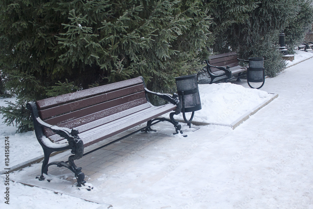 Benches and bins in the snow-covered park. Urban Benches and bins in the snow-covered park. Urban