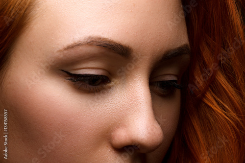 Closeup portrait of a red-haired female model on black background