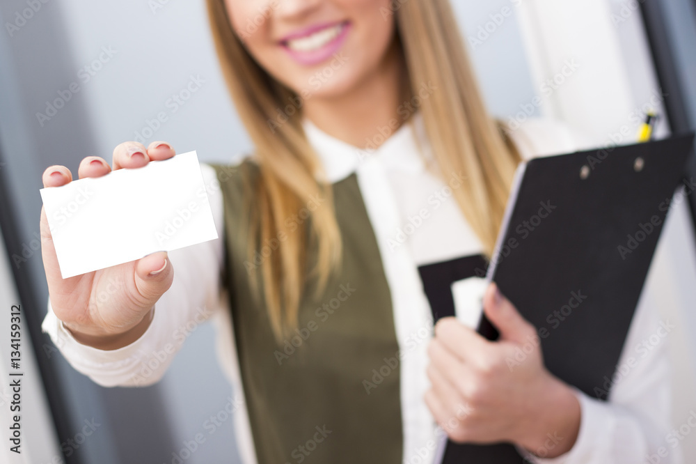 Smiling young business woman holding up her business card. Focus on the card. Smiling young business woman holding up her business card. Focus on the card.