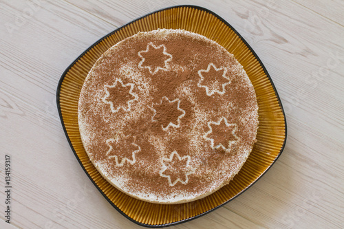 Christmas coffee cake with creamy souffle decorated star on beige wood. Aerial view.