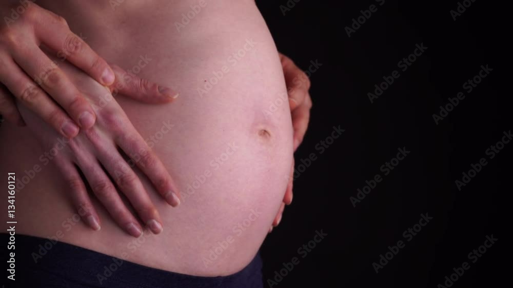 Couple with hands on naked belly of pregnant woman closeup on black background. Pregnancy, parenthood and baby anticipation concept. 4K ProRes HQ codec Couple with hands on naked belly of pregnant woman closeup on black background. Pregnancy, parenthood and baby anticipation concept. 4K ProRes HQ codec