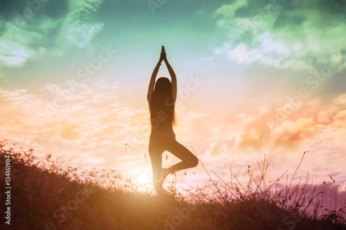 Silhouette of woman praying over beautiful sky background