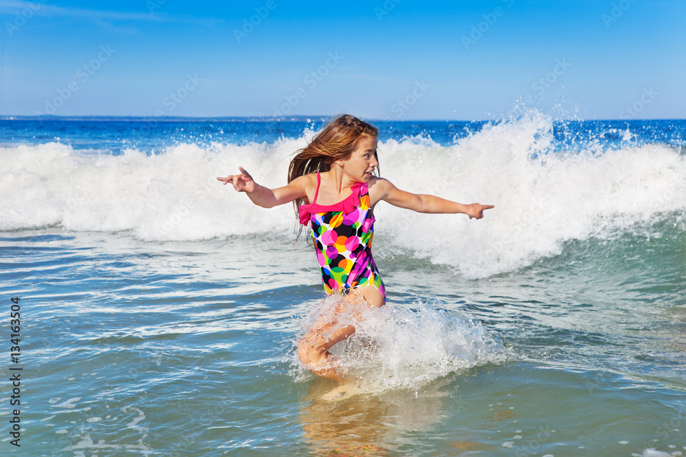 Young girl turning to run from an incoming wave Young girl turning to run from an incoming wave