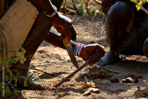 Hadzabe men carving wood to assist in lighting a fire. 