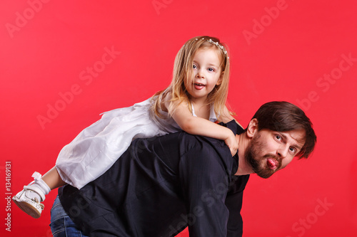 Father and daughter piggyback. They show tongues. Emotional games with your child. Family fun. The joy of communication. Parental support.