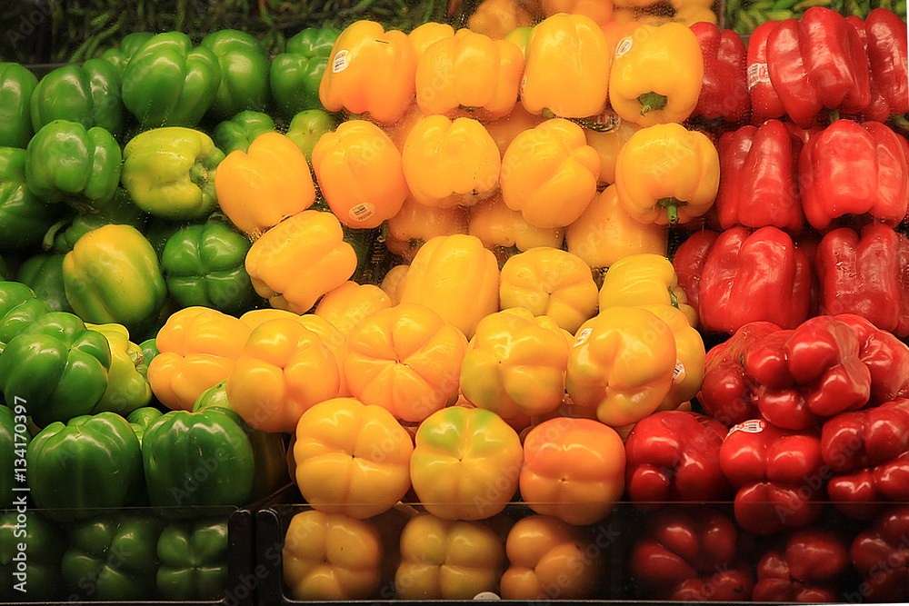 Colorful bell peppers piled in a supermarket.  Includes fresh red, green and yellow bell peppers.