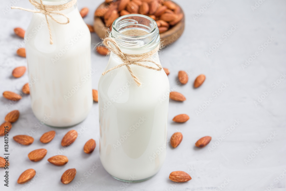 Almond milk in glass bottles with almonds on background, horizontal, copy space Almond milk in glass bottles with almonds on background, horizontal, copy space