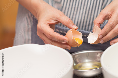 Hands holding egg shell with egg yolk separated