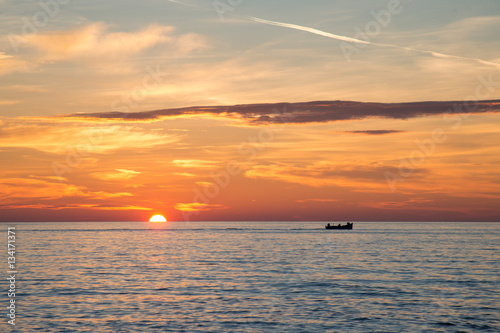 Fishing boat on the background of incredible golden sunrise  clouds and rising sun.