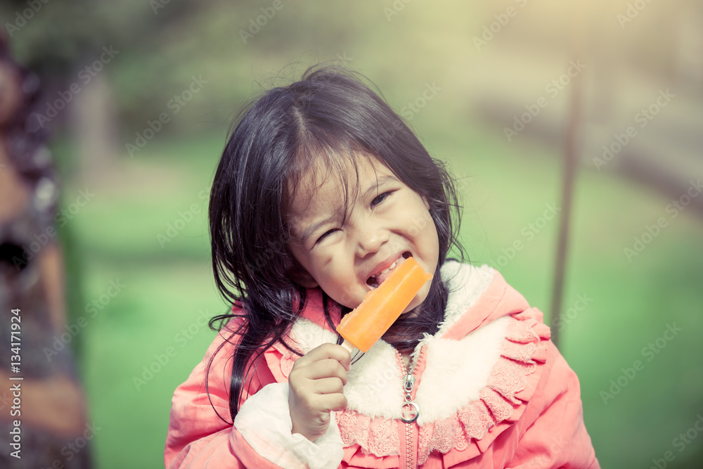 Cute asian little girl is eating ice-cream in the park Cute asian little girl is eating ice-cream in the park