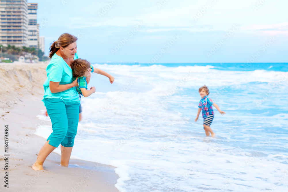 Two little kids boys and mother on the beach of ocean Two little kids boys and mother on the beach of ocean