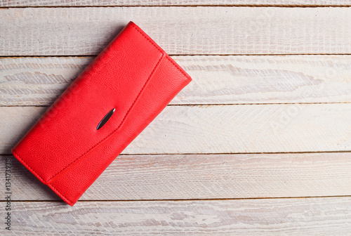 Red purse clutch on a white wooden table.
