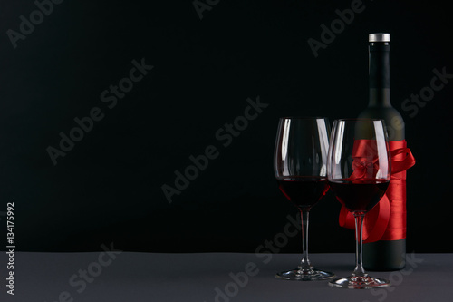 Wine bottle and two wineglasses on a dark background. Love card concept with copy space, Valentine's day theme