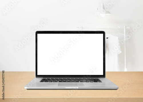 Laptop with blank screen on table against interior background