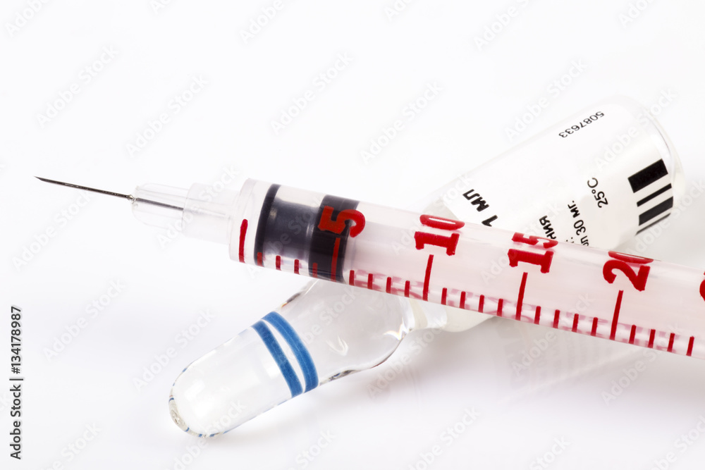 Painkiller drug ampule. Medical syringe lying on the drug vial. Red syringe needle without cap.. White background. Shadows.
