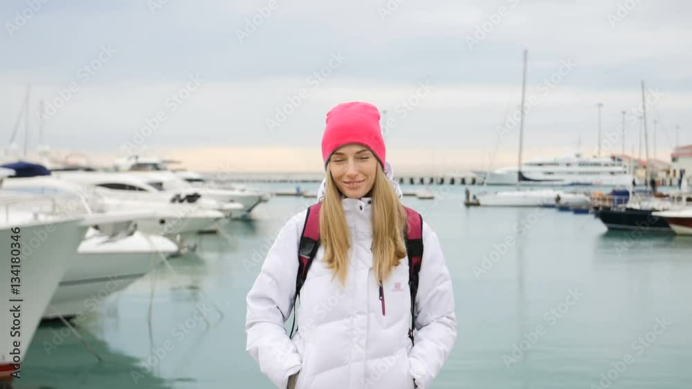 Happy beautiful woman on the pier in front of the yachts