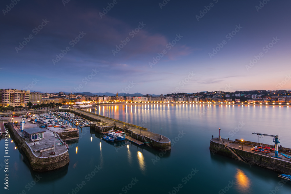 Naklejka premium Illuminated port in San Sebastian at evening twilight