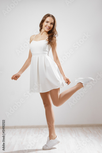 Pretty young girl in white short dress spinning around. Dynamic