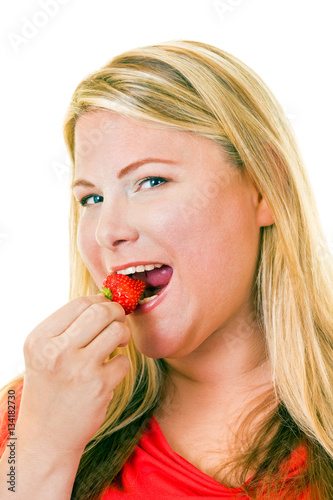Young blond woman eating strawberry.
