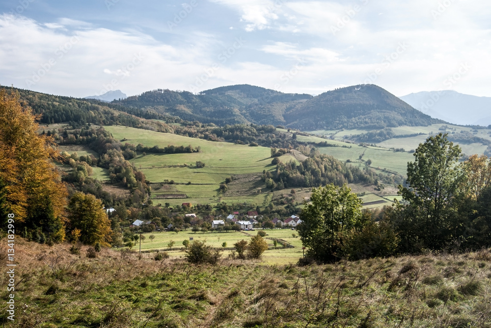 autumn landscape of Kysuce region in Slovakia with Horny Vadicov village, meadows, fields, hills and blue sky with clouds