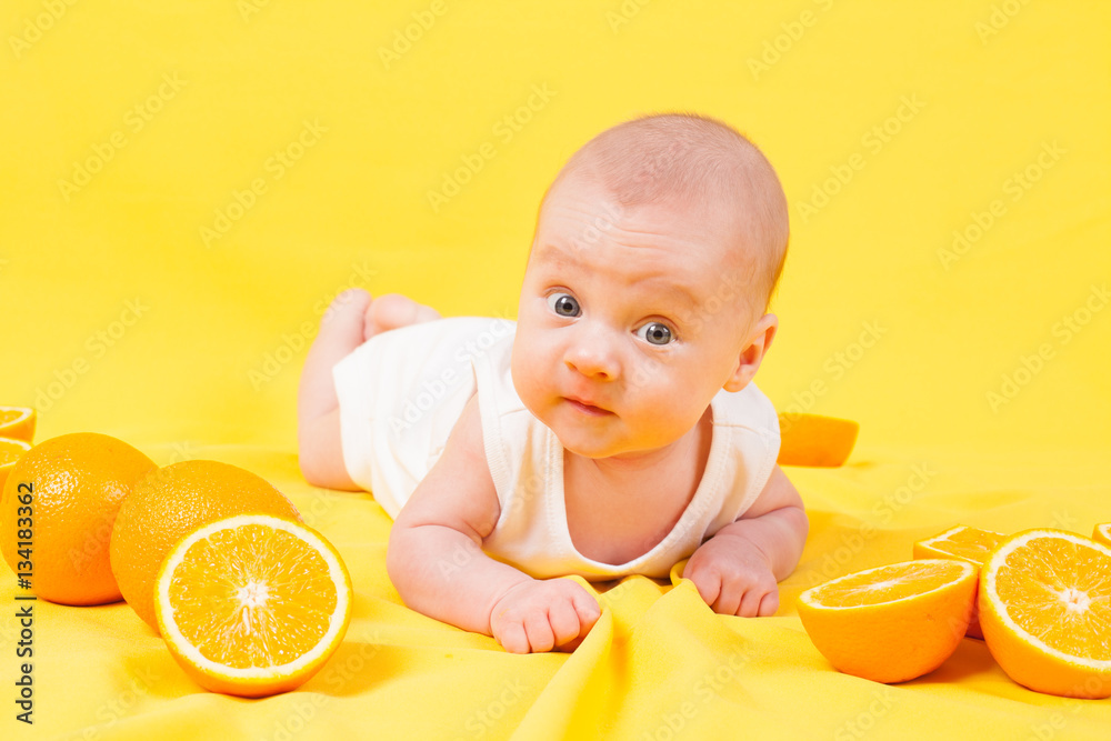 baby boy lies on a yellow with oranges baby boy lies on a yellow with oranges