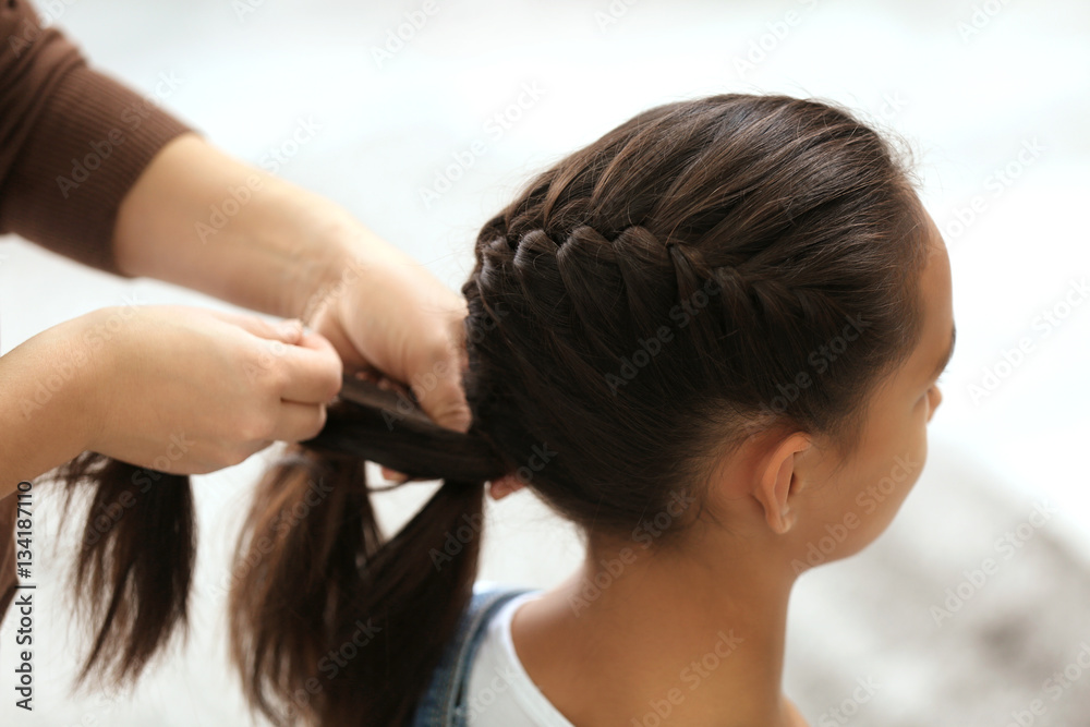 Naklejka premium Woman doing hair of her daughter at home, closeup